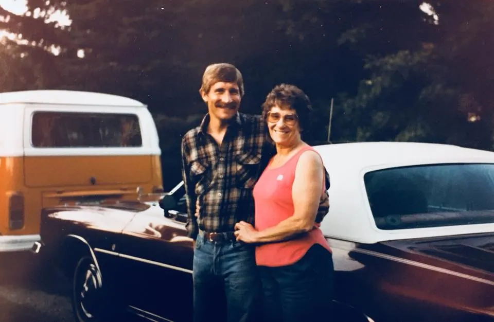 Two people standing beside a restored vintage pickup truck at dusk